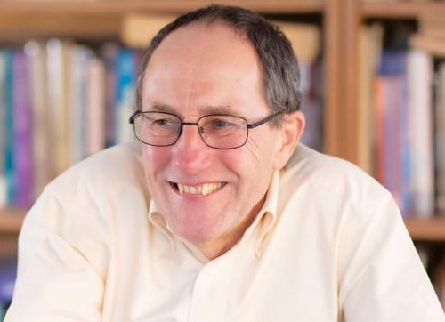 A male sitting at a table in a pale button-down shirt