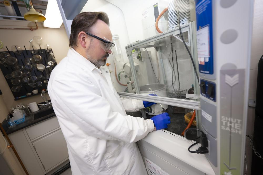 Professor holding a test tube and a sample of a liquid/solid hybrid substance from the test tube on the end of a metal rod