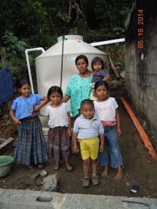 A family stands in front of a new rainwater harvesting system—one of the eight the WPI team installed in May.