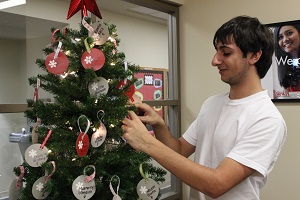 Marc Toomajian ‘17 hangs ornaments on the Giving Tree in the Office of Student Activities. Also assisting in the program are Daniela Ruiz ‘15, Xinyuan (Simon) Zhang ‘18 and Kyla Nicols ‘17.