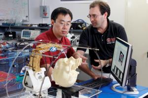 Professor Fischer, right, and graduate student Hao Su with an MRI-guided robot designed to implant electrodes in the brain.